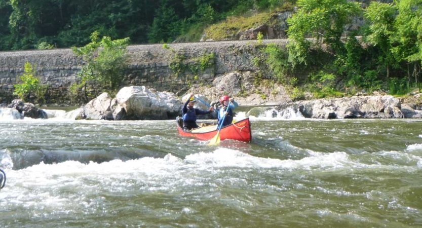 Two students paddle a canoe through whitewater